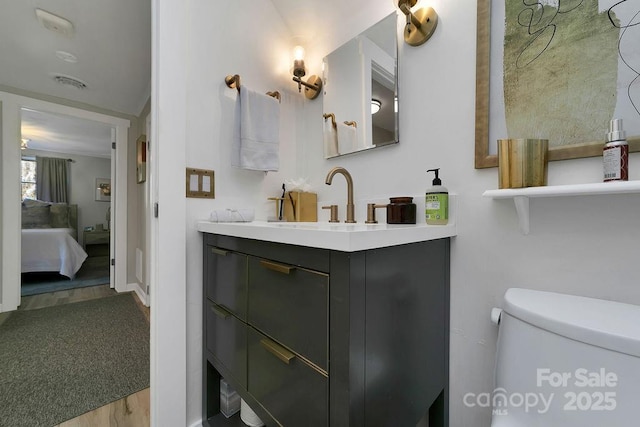 bathroom featuring toilet, ensuite bathroom, wood finished floors, and vanity