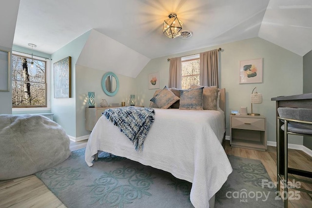 bedroom featuring lofted ceiling, wood finished floors, visible vents, and baseboards