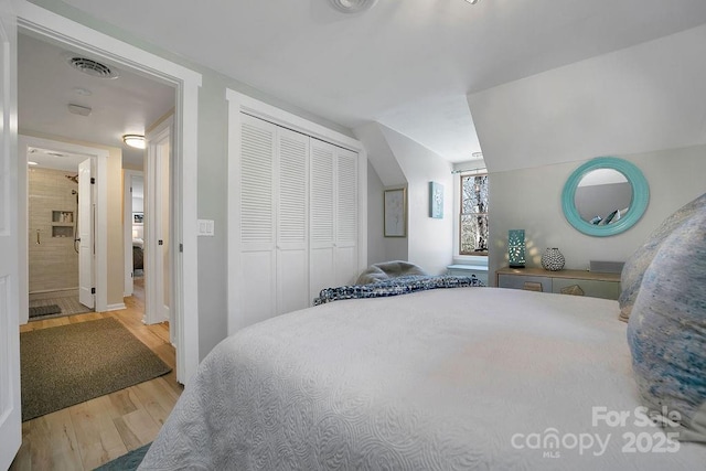 bedroom with a closet, visible vents, and wood finished floors