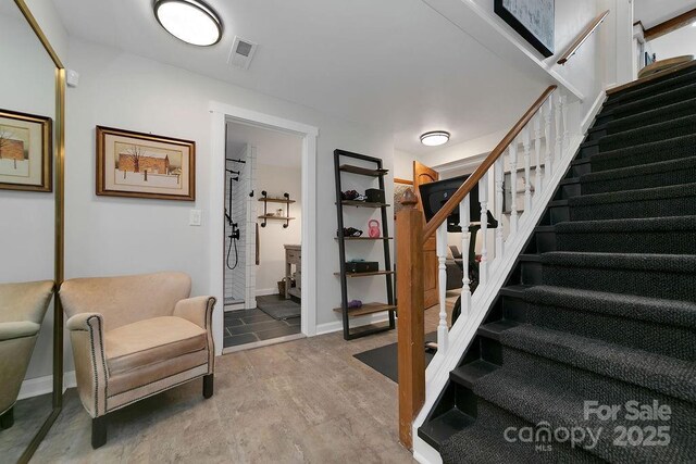 staircase with wood finished floors, visible vents, and baseboards