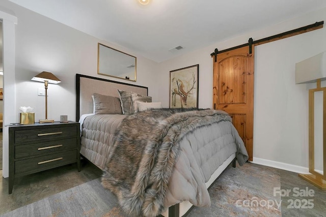 bedroom with a barn door, visible vents, and baseboards