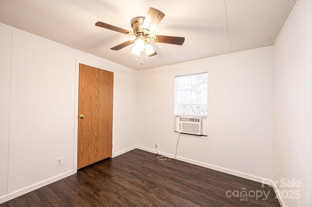 empty room with dark wood-style floors, cooling unit, ceiling fan, and baseboards