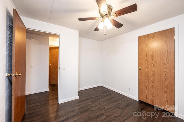 unfurnished bedroom featuring dark wood finished floors, a textured ceiling, baseboards, and ceiling fan