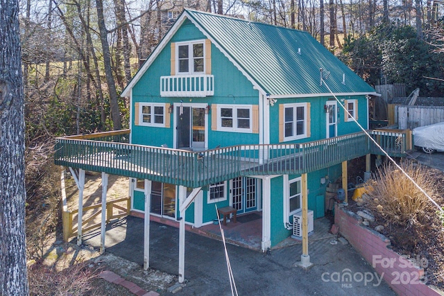 rear view of house featuring metal roof, a deck, ac unit, and a patio