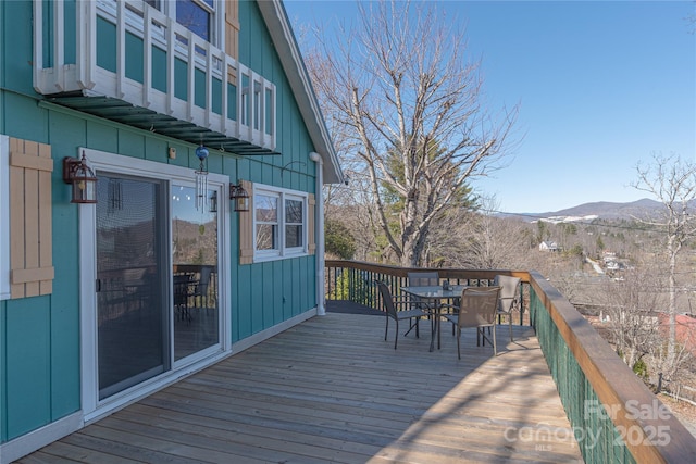 wooden deck with outdoor dining area and a mountain view