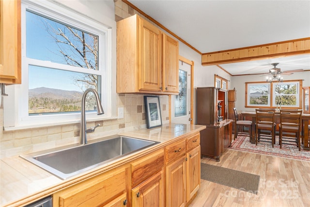 kitchen with light countertops, a sink, light wood-style flooring, and crown molding