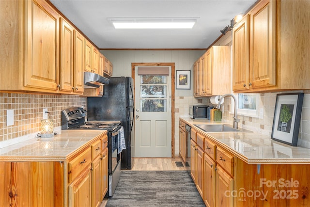 kitchen with black microwave, under cabinet range hood, a sink, light wood-style floors, and electric stove