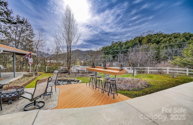 exterior space featuring an outdoor fire pit, an outdoor bar, and fence