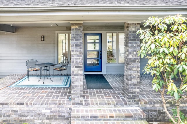 view of exterior entry featuring a shingled roof