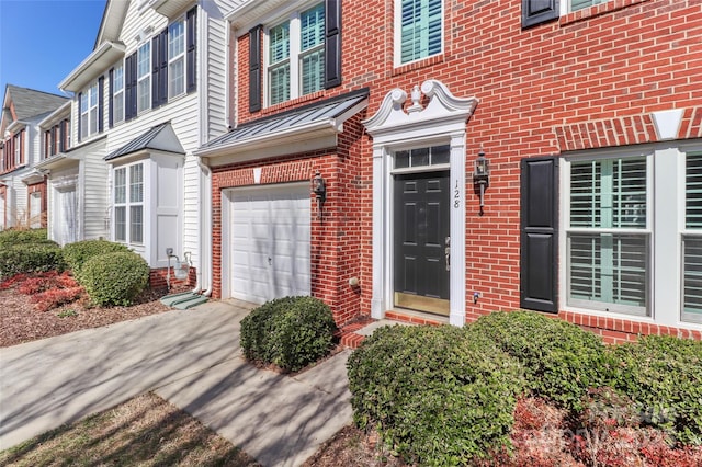 view of exterior entry featuring a garage, driveway, and brick siding