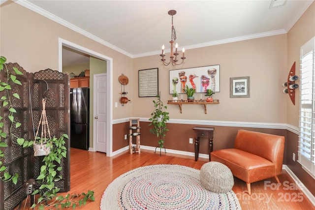 sitting room with a notable chandelier, ornamental molding, wood finished floors, and baseboards