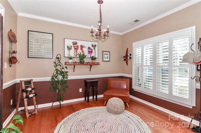 sitting room featuring baseboards, visible vents, wood finished floors, an inviting chandelier, and crown molding