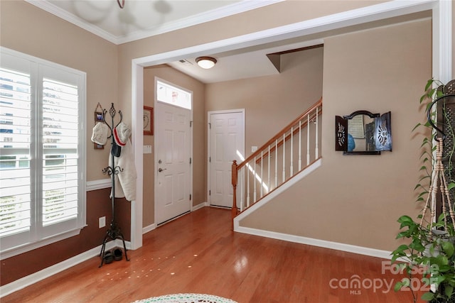 entrance foyer featuring crown molding, wood finished floors, stairs, and baseboards