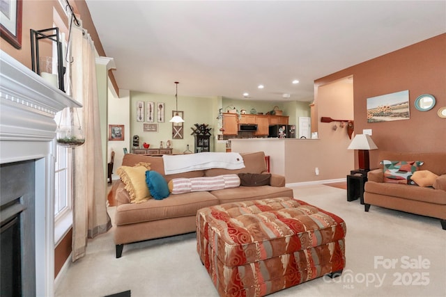 living area featuring baseboards, recessed lighting, a fireplace, and light colored carpet