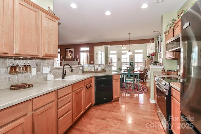 kitchen featuring a peninsula, a sink, light countertops, appliances with stainless steel finishes, and light wood finished floors