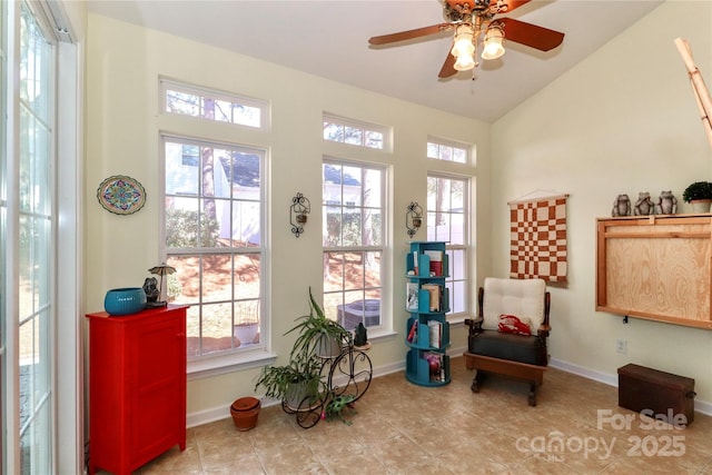 living area featuring a wealth of natural light, vaulted ceiling, baseboards, and ceiling fan