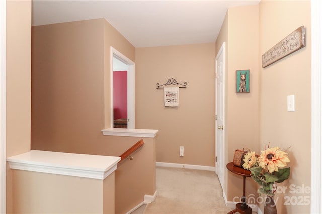 hallway featuring baseboards, an upstairs landing, and light colored carpet