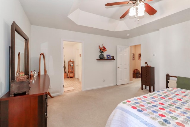 bedroom featuring light carpet, a tray ceiling, a ceiling fan, and baseboards