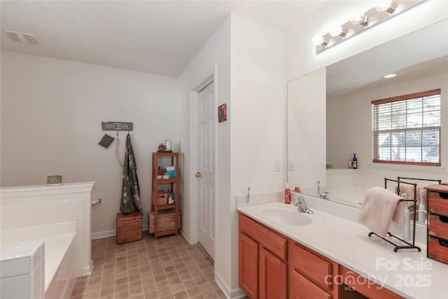 bathroom featuring visible vents, vanity, and a bath