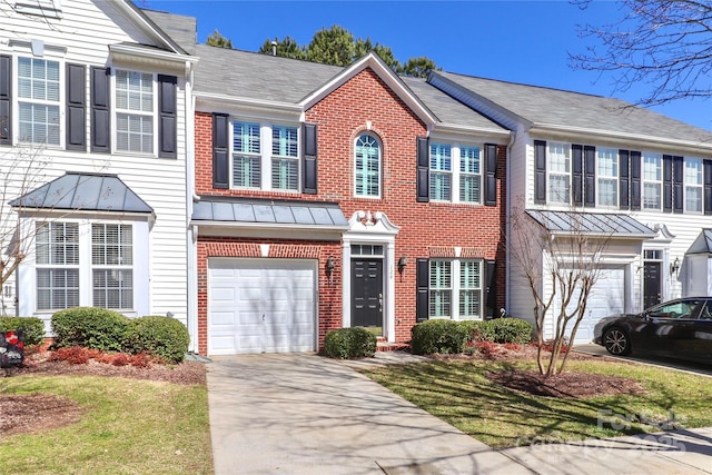 townhome / multi-family property featuring an attached garage, a standing seam roof, concrete driveway, and brick siding