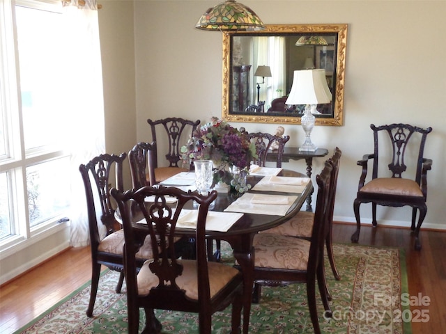 dining space featuring baseboards and wood finished floors