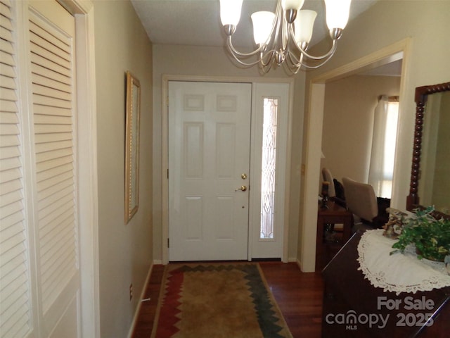 foyer entrance featuring wood finished floors, baseboards, and an inviting chandelier