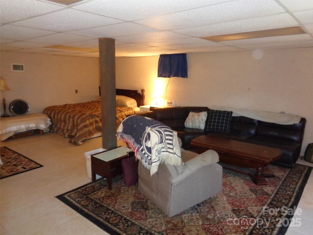 tiled living area with a drop ceiling and visible vents