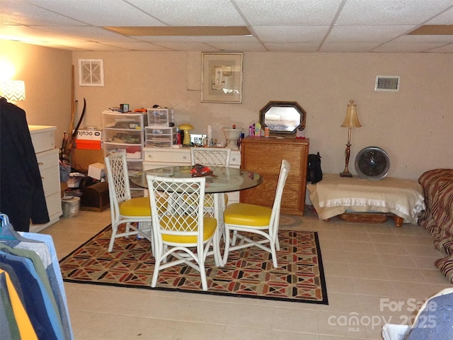 dining space with a paneled ceiling, light tile patterned flooring, and visible vents