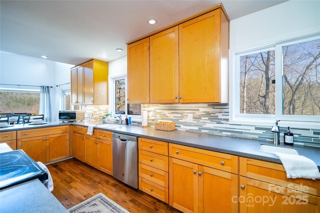 kitchen with appliances with stainless steel finishes, dark countertops, a sink, and a wealth of natural light