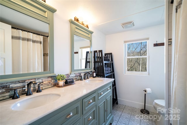 full bathroom featuring double vanity, a sink, visible vents, and baseboards