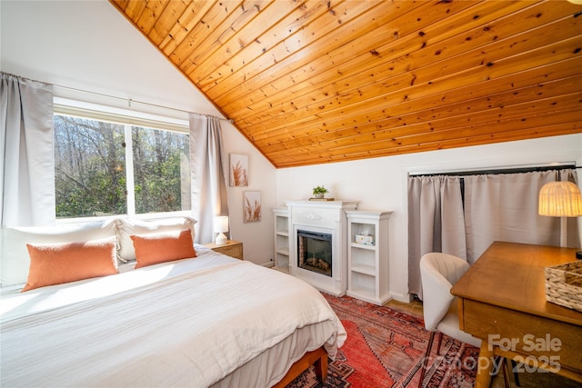 bedroom featuring lofted ceiling, wood ceiling, and a glass covered fireplace