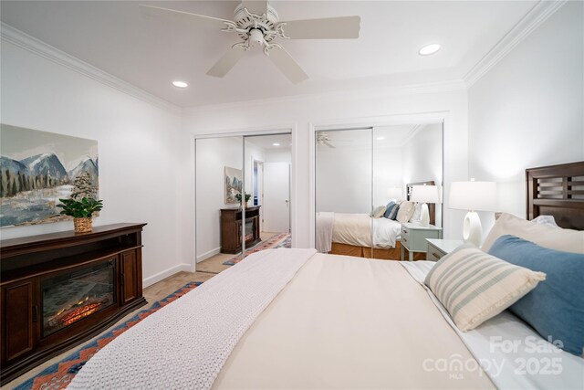 bedroom with ceiling fan, recessed lighting, two closets, a glass covered fireplace, and crown molding