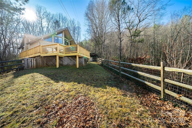 exterior space with fence, a wooden deck, and a lawn