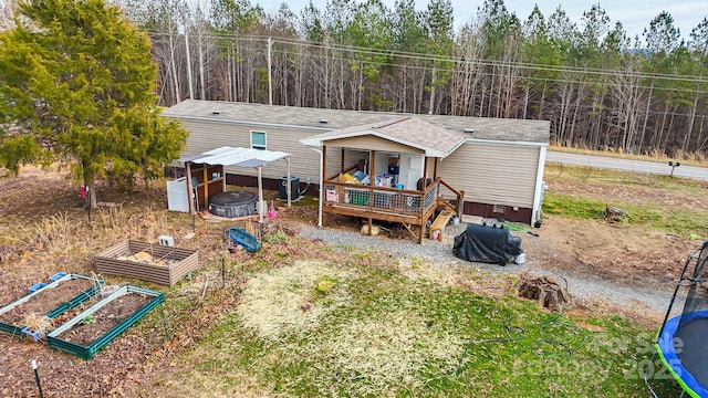 back of property with a shingled roof, a vegetable garden, and a wooden deck