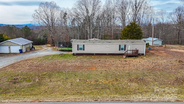 manufactured / mobile home featuring an outbuilding, a trampoline, and a view of trees