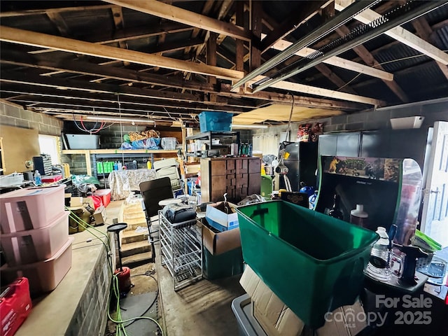 miscellaneous room featuring lofted ceiling, concrete block wall, and unfinished concrete floors