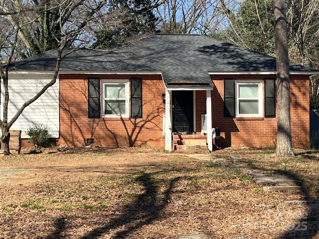 view of front of property featuring a shingled roof, crawl space, and brick siding