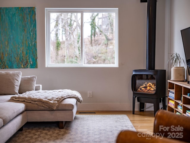 sitting room featuring visible vents, wood finished floors, and a wood stove