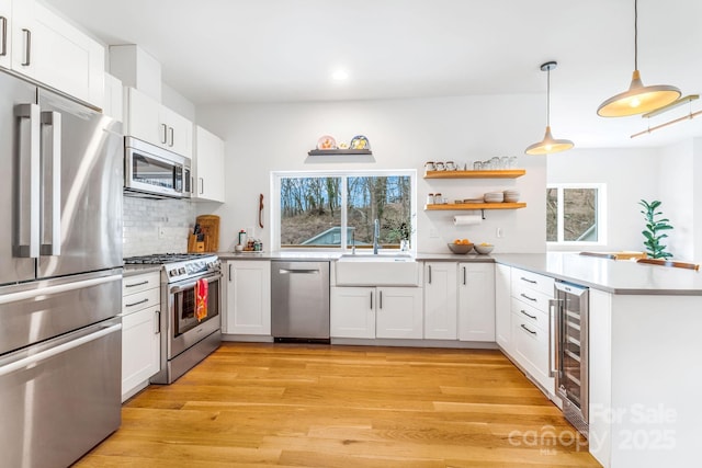 kitchen featuring light wood-type flooring, wine cooler, appliances with stainless steel finishes, a peninsula, and white cabinets