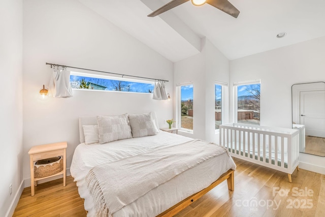 bedroom featuring baseboards, high vaulted ceiling, light wood-style floors, and a ceiling fan