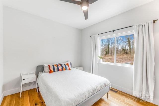 bedroom featuring visible vents, baseboards, wood finished floors, and a ceiling fan