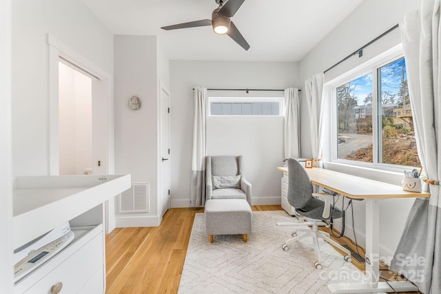 home office featuring ceiling fan, baseboards, visible vents, and light wood-type flooring