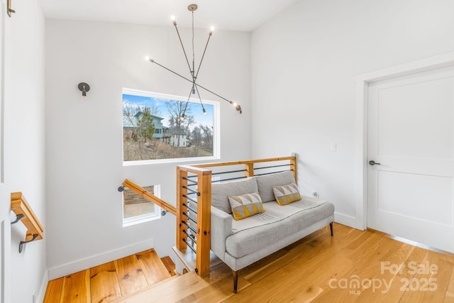 living area with a notable chandelier, an upstairs landing, wood finished floors, and baseboards