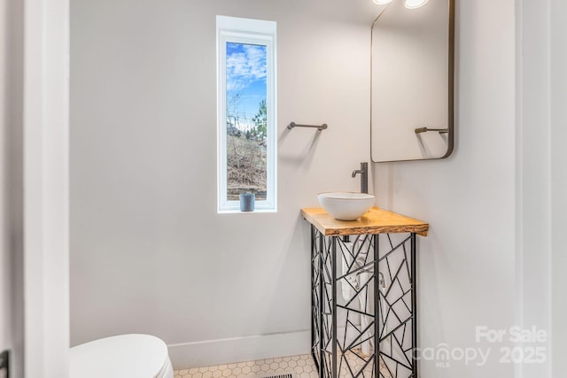 half bathroom featuring toilet, vanity, and baseboards