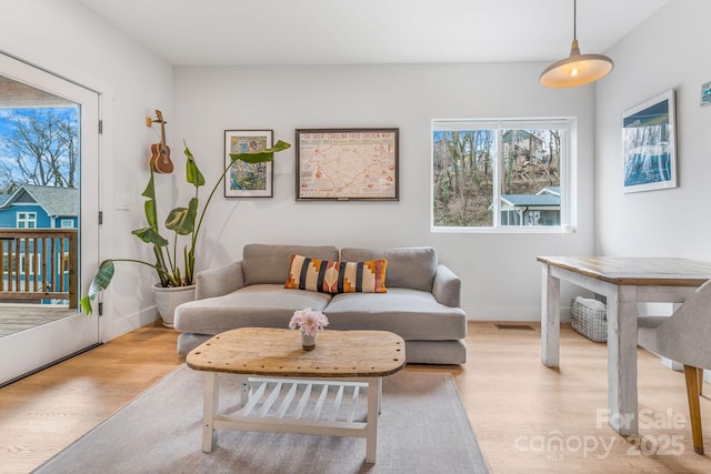 living area featuring visible vents, wood finished floors, and baseboards