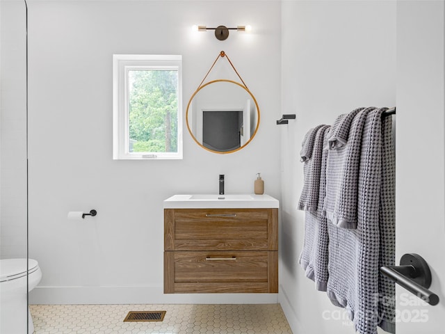 bathroom with vanity, baseboards, visible vents, tile patterned floors, and toilet