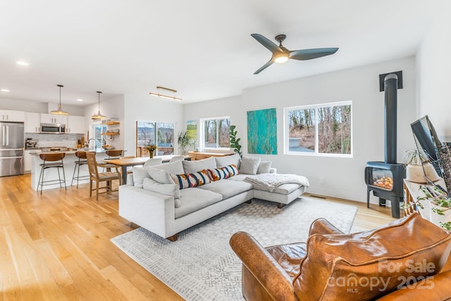 living area featuring visible vents, a wood stove, recessed lighting, ceiling fan, and light wood-style floors