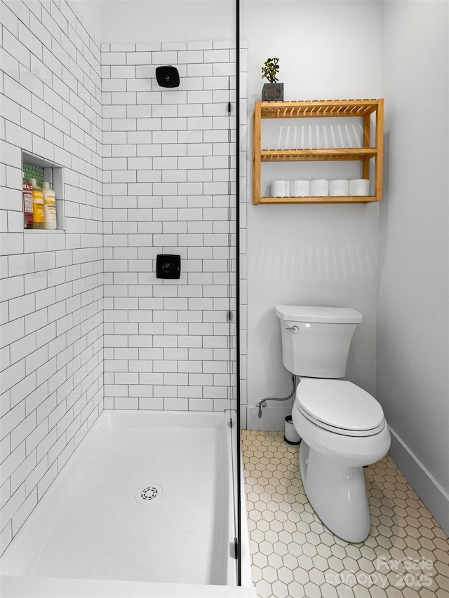 bathroom featuring a shower stall, toilet, baseboards, and tile patterned floors