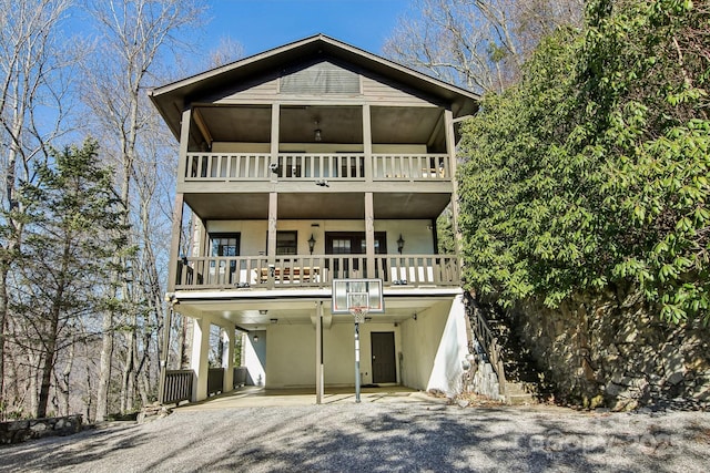 view of front of home with stairway, driveway, a balcony, and stucco siding