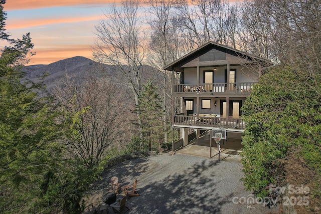 view of front facade with a mountain view, driveway, a carport, and a balcony